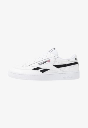 Zapatillas de cuero blancas con acentos negros, con un diseño de corte bajo, caja de dedos perforada y suela de goma texturizada. Logo de Reebok en el costado.