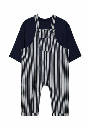 Blaue gestreifte Latzhose mit einem navyfarbenen T-Shirt. Die Latzhose verfügt über große Fronttaschen, verstellbare Träger und umgekrempelte Säume an den Knöcheln.