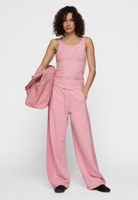 Roze geribbelde tanktop met een klein logo, gecombineerd met losse roze joggingsbroek met een elastische tailleband en zijzakken.