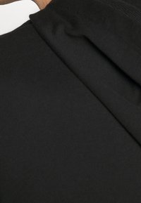 Tejido negro que muestra una textura suave con un acabado liso, con un diseño plegado que resalta la superposición y la elegancia.