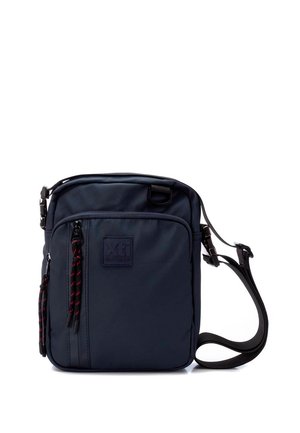 Bolso bandolera azul marino hecho de material resistente, con un frente texturizado, un parche de logo prominente y tiradores de cremallera en contraste rojo y negro.