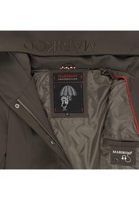Braune Marikoo-Jacke geöffnet, um die Innenfutter-Patches zu zeigen, eines mit dem Markennamen und einem Regenschirm-Graphic und ein weiteres mit einem Kopfhörer-Icon.