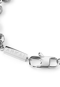 Metal bracelet with decorative links, featuring a polished silver finish, a tag engraved "ARKAI," and a sturdy lobster clasp.