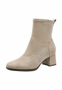Beżowe zamszowe botki za kostkę na słupku, z okrągłym noskiem i pętelką z tyłu, zaprezentowane na białym tle.
