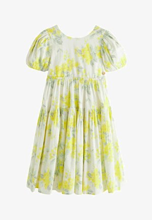 Virágmintás, könnyű pamutból készült ruha sárga és zöld virágrajzokkal. Puffos ujjak, ráncolt derék és réteges szoknya jellemzi.