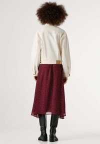 Balta džinsinė striukė derinama su bordine sijono taškuotomis detalėmis, kuriame vyrauja laisvas dizainas. Juodi aukšti iki kelių batai užbaigia aprangą.