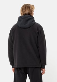 Giacca in pile nera con cappuccio grigio, superficie testurizzata, polsini elasticizzati e vestibilità comoda. Presenta una cucitura visibile lungo il retro.