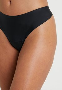 Black bikini bottom with a smooth texture, high-waisted design, and minimal seams. Features a classic cut and seamless edges for comfort.