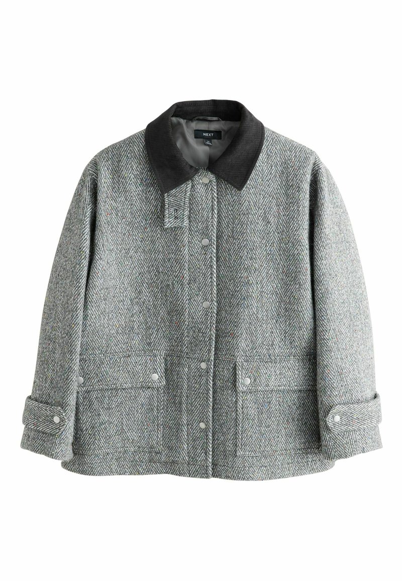 Harmaa herringbone-takki mustalla farkkukollarilla, nepparilla ja kahdella etutaskulla. Kankaan pinta on tekstuuri- ja kuviomaisempi.