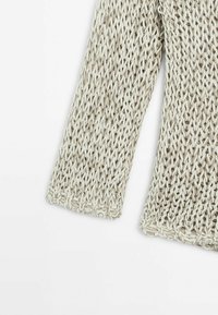 Licht beige gebreide trui met een open structuur, voorzien van lange mouwen en een comfortabele pasvorm. De gestructureerde stof voegt diepte toe.