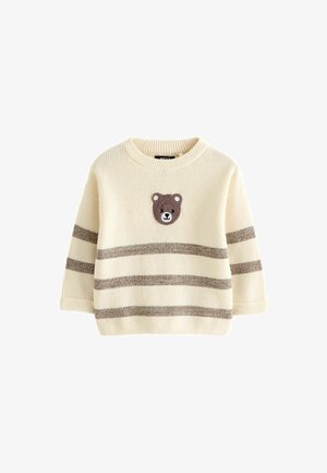 Kremowy sweter dzianinowy z naszywką przedstawiającą brązową twarz niedźwiedzia na piersi oraz trzema poziomymi brązowymi paskami na rękawach i korpusie.