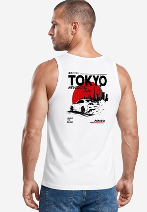 Mann trägt weißes ärmelloses Shirt mit Grafik eines Tokyo-Drift-Autos und roter Sonne hinter der Stadtsilhouette auf dem Rücken.