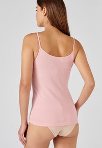 Roze geribbelde tanktop met dunne bandjes, heeft een aansluitende pasvorm en een gladde textuur; de achterkant toont de halslijn en naden.