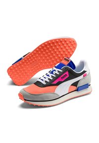 Paire de baskets Puma avec des accents blancs, gris, orange, noir, bleu et rose, présentant des semelles texturées orange et des lacets blancs.