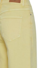 Jeans in denim giallo chiaro con una tasca posteriore con alette appuntite, etichetta in pelle sulla vita e dettagli di cucitura sottili.