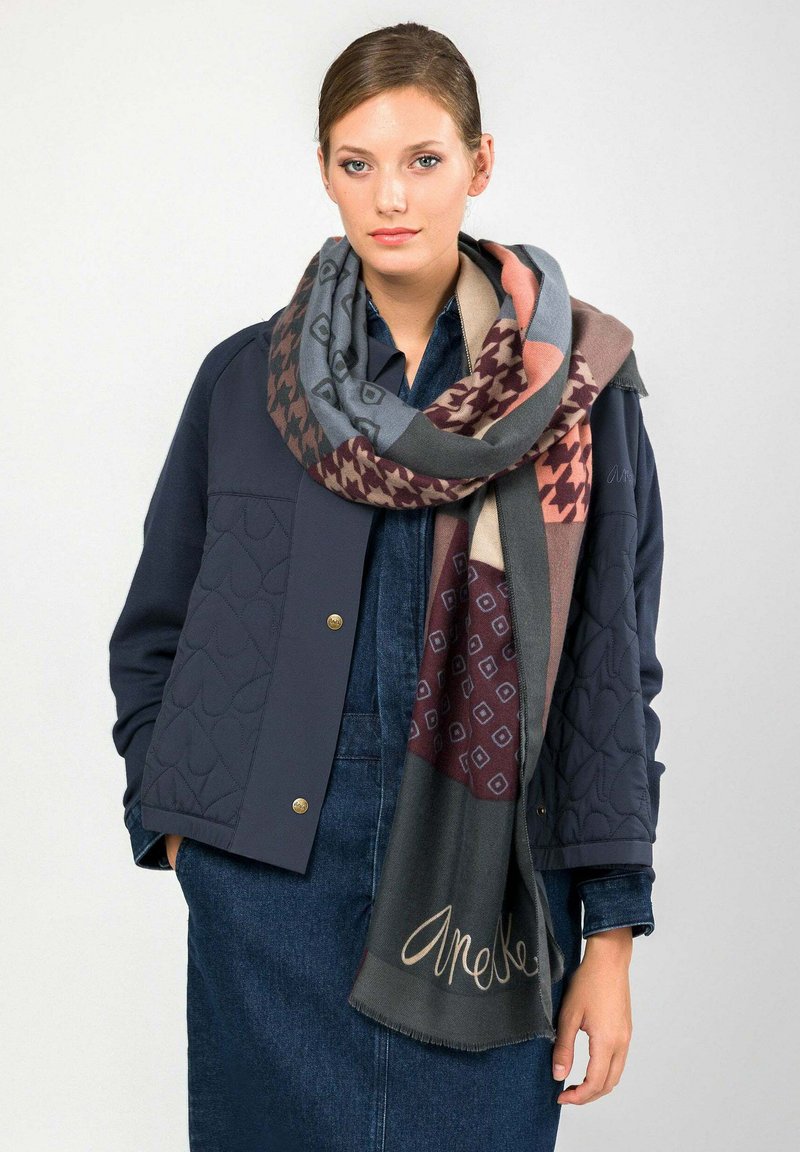 Sciarpa avvolgente a motivi multipli con tonalità di grigio, bordeaux e pesca; realizzata in tessuto morbido con bordi sfrangiati e dettaglio marchiato.
