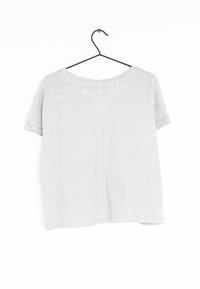 Camiseta gris de manga corta con un cuello redondo, hecha de algodón suave, que presenta un ajuste relajado y un diseño simple. Cuélga en un gancho de metal negro.