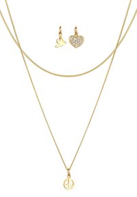 Guldtonad lagerhalsband med en fredssymbolpendel, prydd med en fågel och ett hjärtcharm med rhinestones.