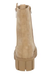Bottine en daim beige avec une fermeture éclair, dotée d'une semelle épaisse et texturée et d'un design simple et épuré. Finition lisse avec des accents minimaux.