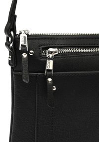 Sac à main en cuir noir avec surface texturée, compartiments à double fermeture éclair, quincaillerie en argent et bandoulière réglable. Design minimaliste.
