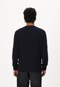 Ναυτικό μπλε πλεχτό πουλόβερ με στρογγυλή λαιμόκοψη, μακριά μανίκια και ριμπ μανσέτες και στρίφωμα. Υφασμάτινη επιφάνεια, μινιμαλιστικός σχεδιασμός.