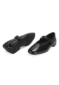 Schwarze Lederflachschuhe mit runder Zehenform, einem Riemen über dem Spann und einer strukturierten Gummisohle. Glatte Oberfläche mit minimalen Details.