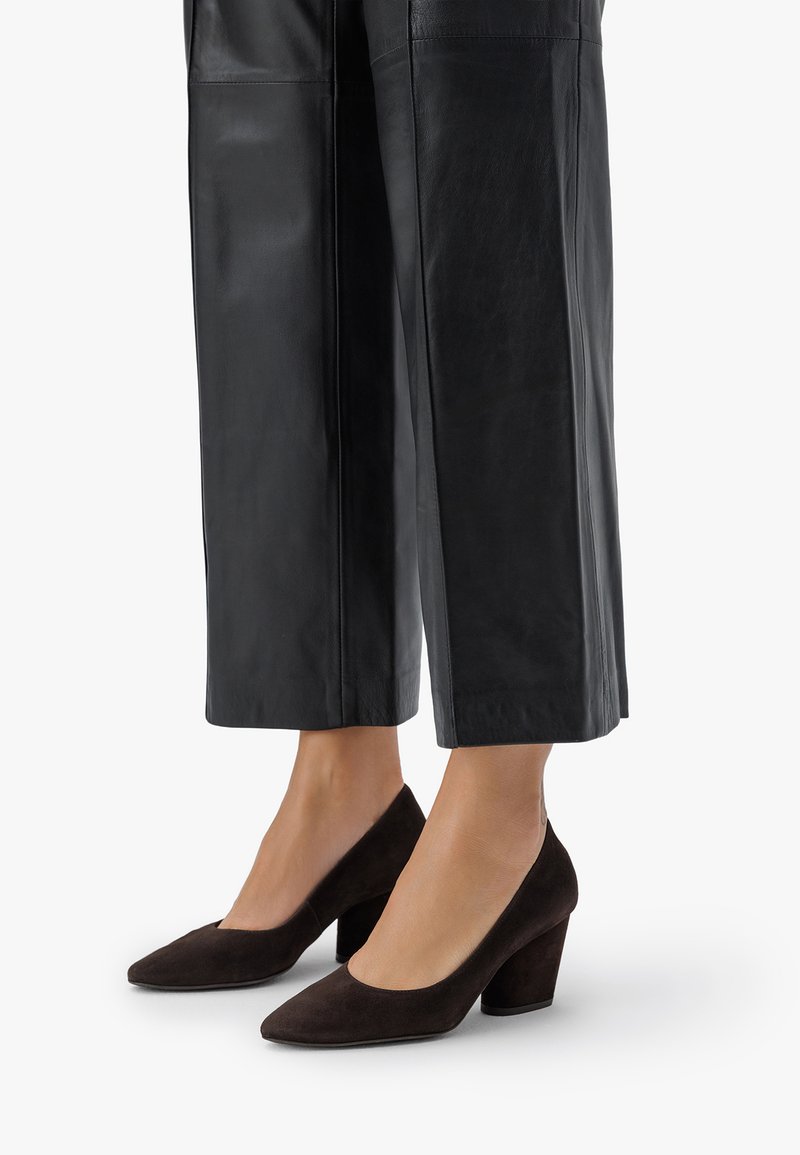 Ruskeat mokkasaappaat korolla, joissa on terävä kärki ja paksu korko, yhdistettyinä mustiin nahkasiipiin.