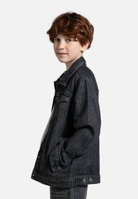 Jeansowa kurtka w ciemnym odcieniu, z klasycznym kołnierzykiem, zapięciem na guziki z przodu i bocznymi kieszeniami. Miękka tekstura z luźnym krojem i minimalnymi detalami.