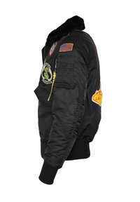 Svart bomberjacka med en krage klädd i päls, som har flera broderade lappar, dragkedjestängning och ribbade ärmslut. Sateenliknande yta.