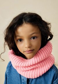 Scialle a collo in maglia a costine rosa avvolge il collo, abbinato a una giacca di denim. Texture morbida con un aspetto spesso e accogliente.