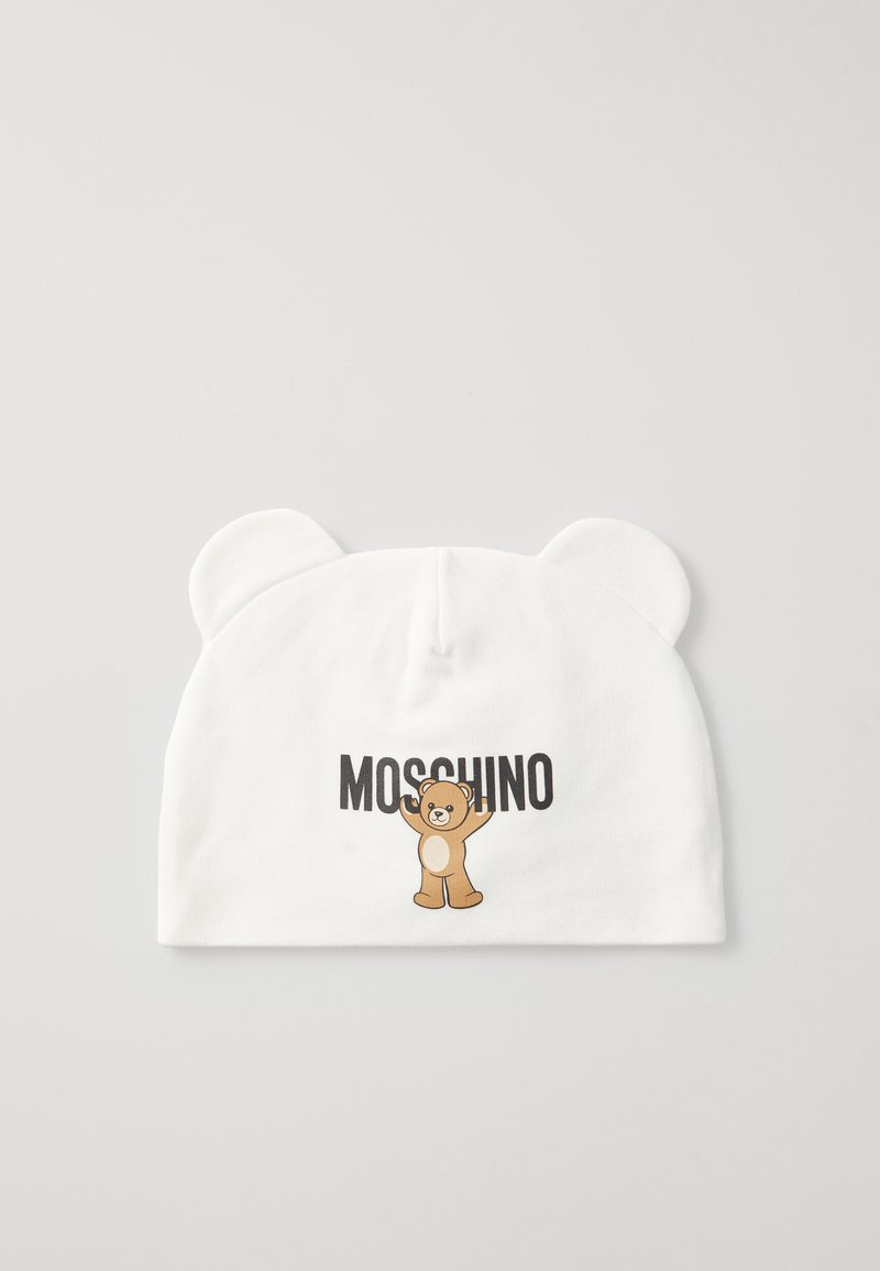 Gorro branco com orelhas de urso, apresentando um gráfico de urso de pelúcia e o texto "MOSCHINO" em preto. Feito de um tecido suave, de textura lisa.