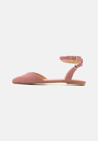 Bailarinas de ante rosa con punta afilada, tira de tobillo sujeta por una hebilla dorada y suela plana para mayor comodidad. Diseño minimalista con recortes.