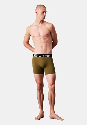 Boxers pour hommes de la marque G-STAR en vert olive avec une ceinture noire arborant des lettres blanches, tissu lisse, coupe ajustée.