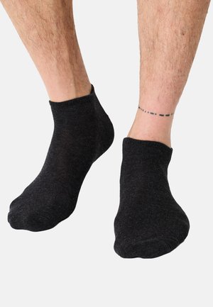 Calzini alla caviglia in cotone nero con una texture a coste, caratterizzati da una finitura liscia e un design a taglio basso intorno alla caviglia, lasciando la pelle scoperta sopra.