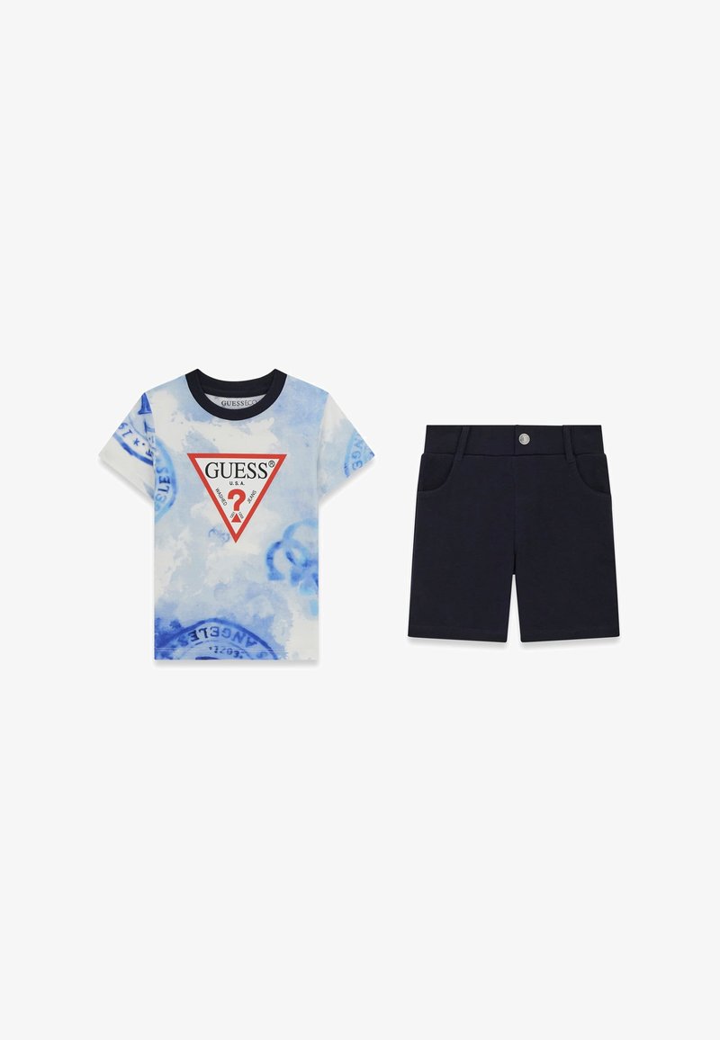 Niebiesko-biała koszulka z krótkim rękawem w stylu tie-dye z logo, zestawiona z jednolitymi ciemnogranatowymi szortami z kieszeniami z przodu i zapięciem na guziki.