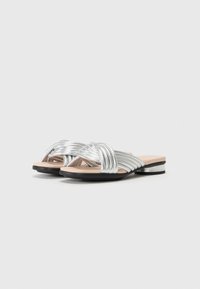Silver platta sandaler med flätade remmar, syntetmaterial, ljusbeige innersula och en låg svart klack. Slät yta, modern design.