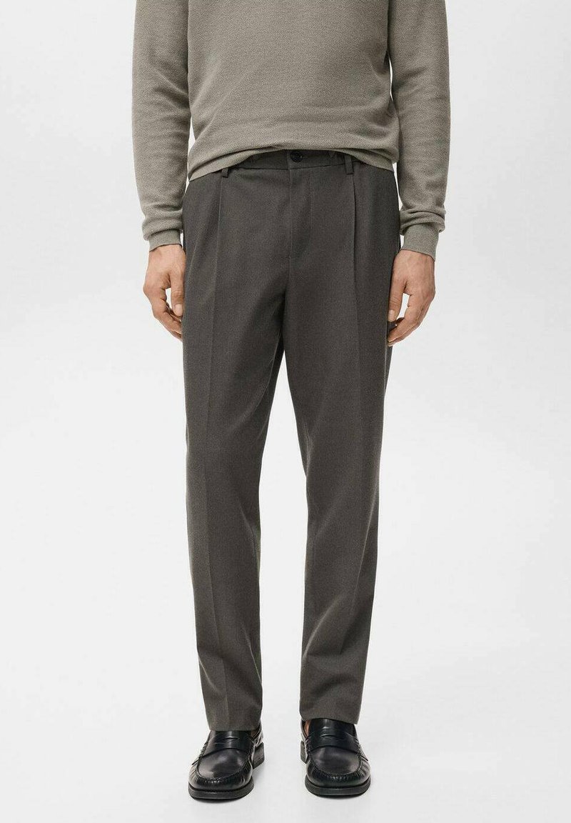 Sive hlače s pregibi, narejene iz gladkega blaga. Nositve z ustreznim svetlo sivim puloverjem in črnimi mokasini.