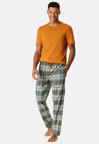 Een oranje katoenen t-shirt gecombineerd met een geplaid pyjamabroek in groen, blauw en oranje tinten, met een trekkoord in de taille en een relaxed fit.