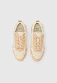 Bež i krem tenisice s glatkim kožnim gornjim dijelom, kontrastnim teksturiranim panelima i dizajnom na vezanje, s jastučićnim potplatom i detaljem s logotipom.