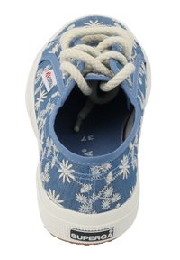 Sneaker in tela blu con ricami floreali bianchi, lacci crema e suola in gomma testurizzata. Presenta una punta tonda e un design a profilo basso.
