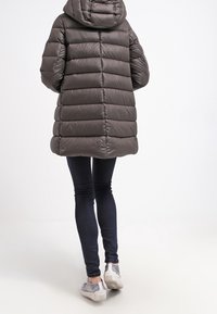 Heather grijze pufferjack met een capuchon, voorzien van horizontaal gestikte delen, met een cinched taille en een lengte tot halverwege de dij. Gemaakt in combinatie met donkere jeans.