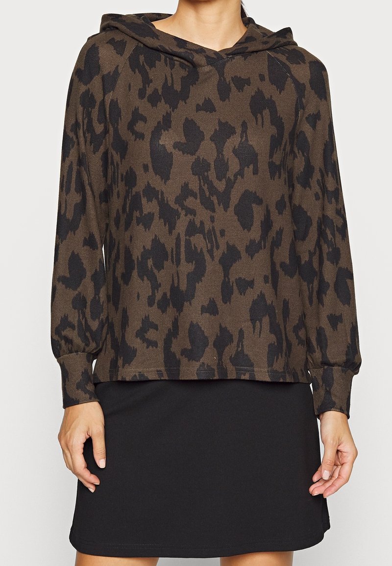 Felpa marrone con motivo leopardato nero, caratterizzata da una vestibilità comoda, maniche lunghe e cappuccio con coulisse. Abbinata a una gonna nera.