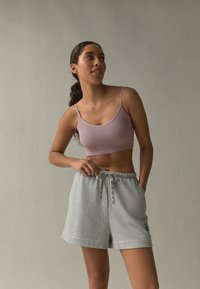 Reggiseno sportivo viola chiaro a coste abbinato a morbidi shorts in cotone grigio chiaro con vita elastica e coulisse. Design semplice e confortevole.