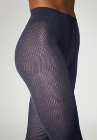 Leggings blu navy con motivo a nido d'ape e ampia fascia elastica in vita. Il tessuto sembra elasticizzato e aderente.