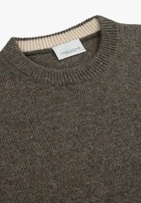 Brunstickad tröja med ribbad rundhals och beige detalj vid kragen. Materialet verkar ha en texturerad yta med en varm och mjuk finish.