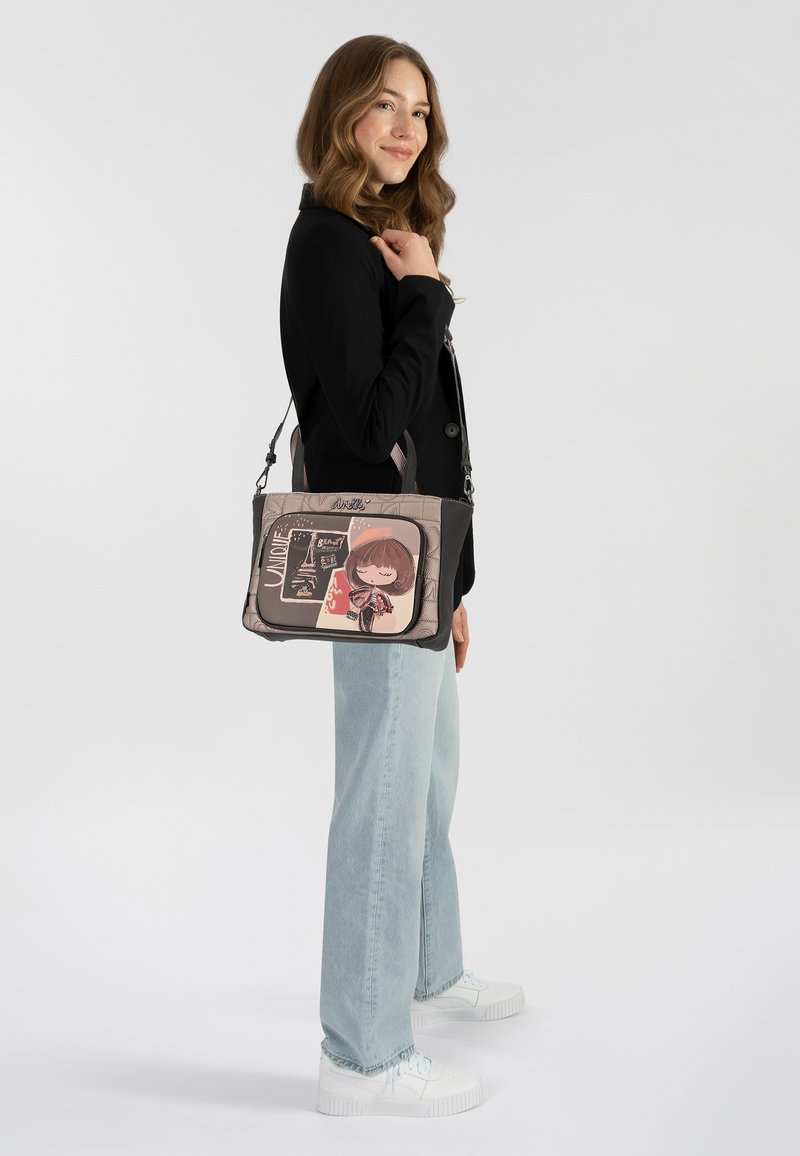 Borsa a spalla nera e grigia con un design a cartone animato fantasioso, dotata di chiusura a zip e tracolla regolabile. Tessuto liscio e strutturato.