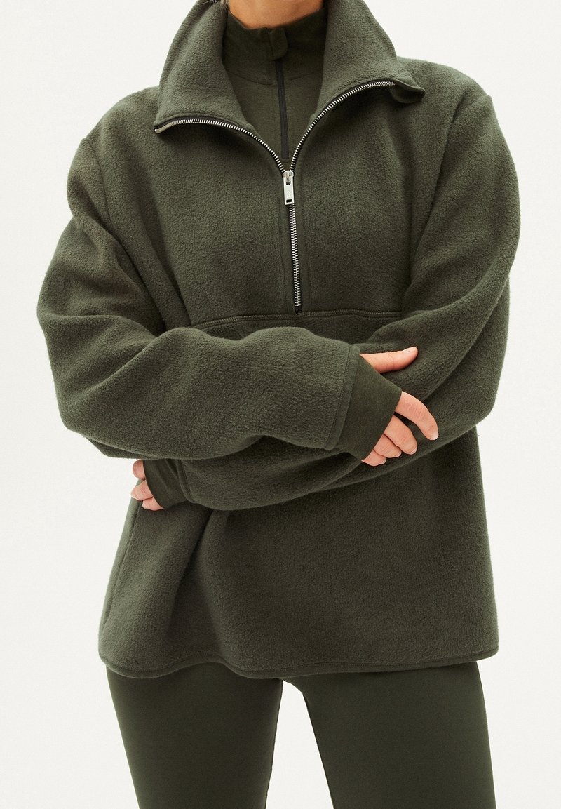 Pullover in pile verde scuro con colletto alto, zip frontale a metà e vestibilità ampia. Caratterizzato da maniche lunghe e una superficie morbida e texture.