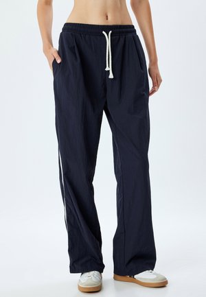 Marineblauwe lichtgewicht broek met een elastische tailleband, een trekkoordsluiting, zijzakken en contrasterende witte zijstrepen.