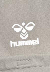 Grå stof med en tekstureret overflade præsenterer et hvidt logo med en stiliseret bi og ordet "hummel" i fed skrift.