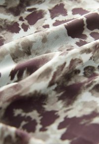 Texturerad tyg i nyanser av grädde, brunt och taupe, med ett prickigt mönster, har mjuka, flödande draperingar och ett lätt utseende.